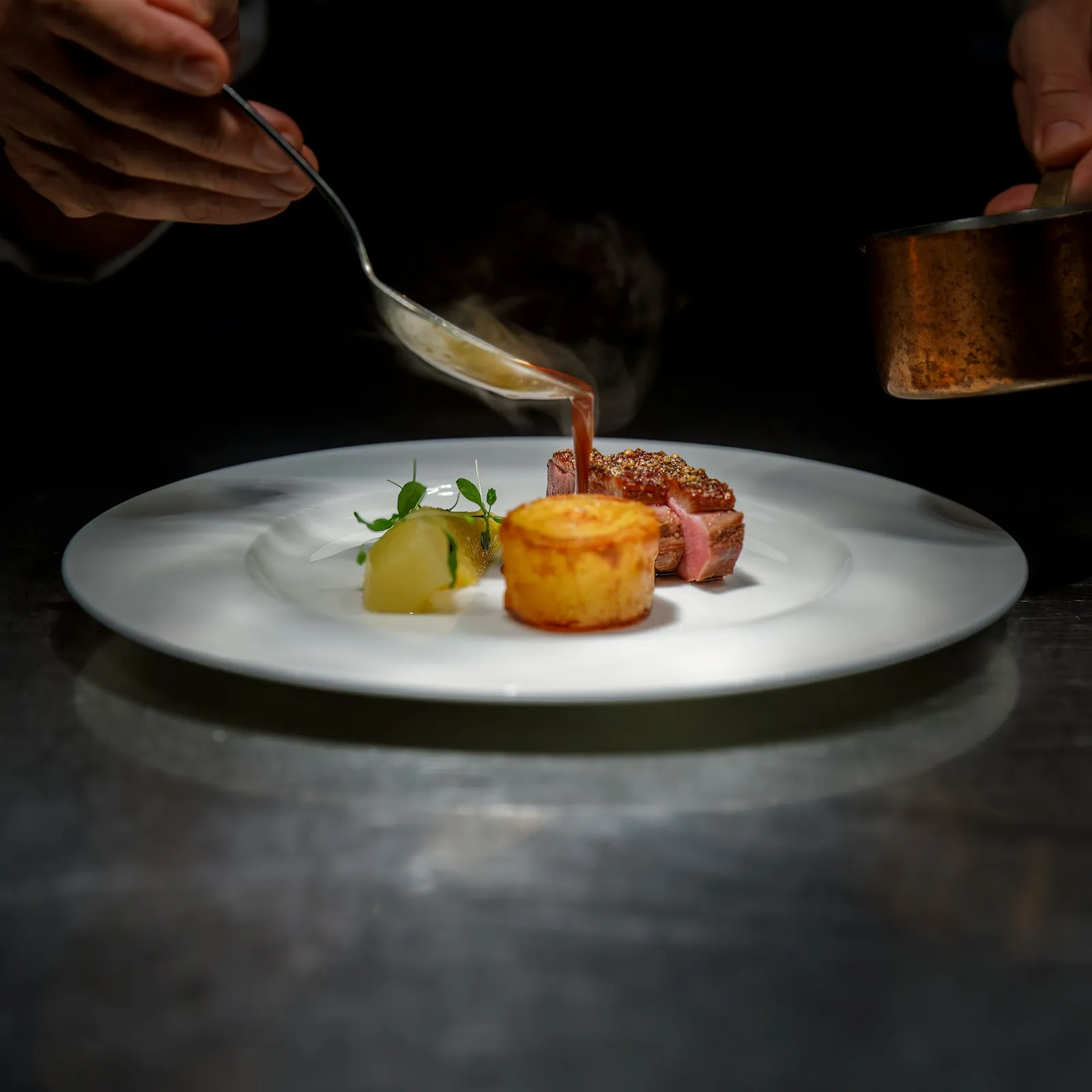 Chef nappant de sauce une assiette dressée